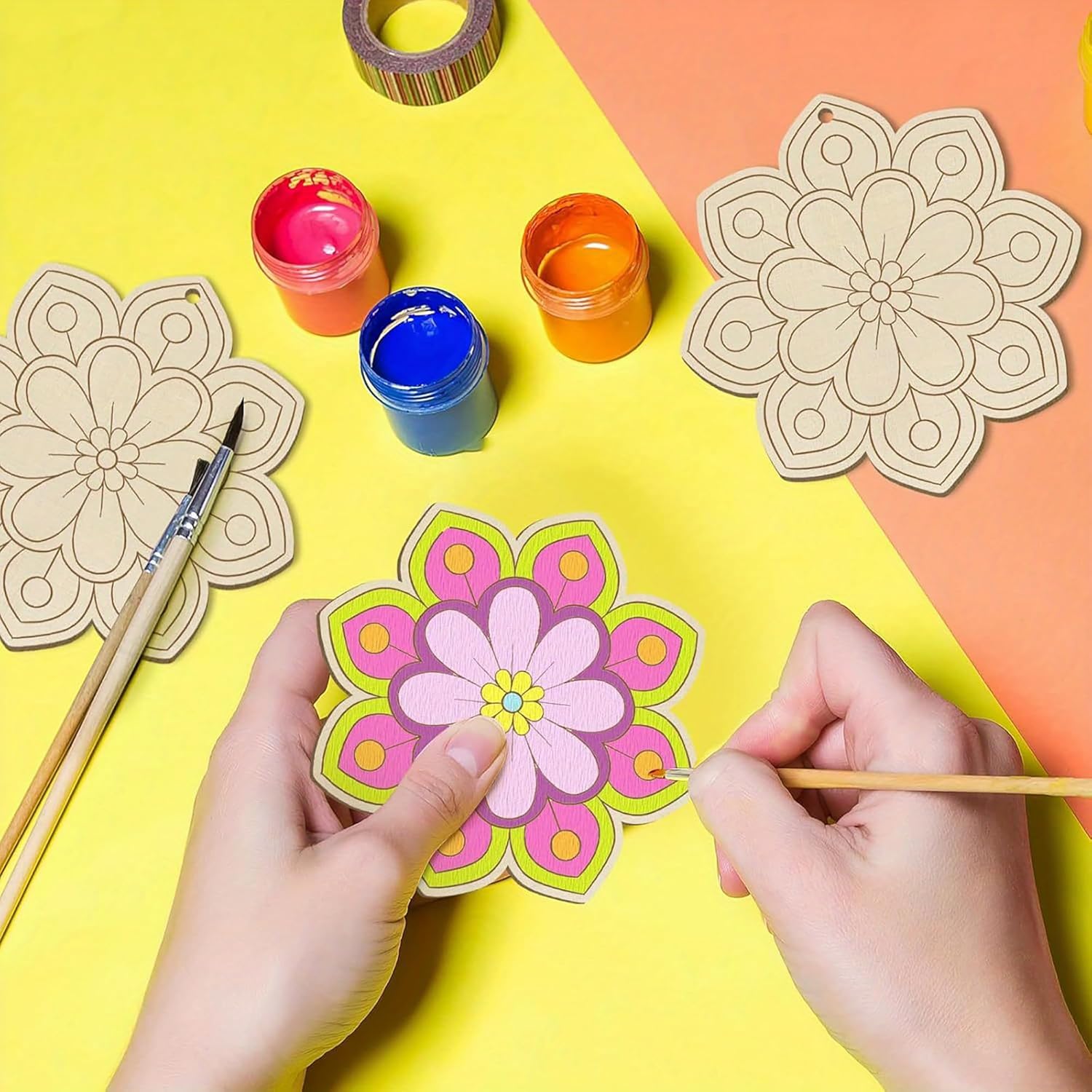 Colorful paper flower craft on a yellow and orange background with paint containers and tools.
