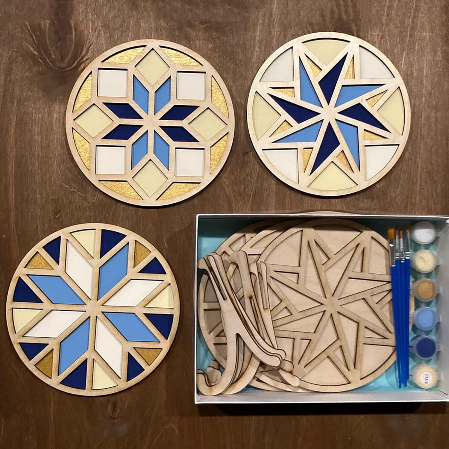 Wooden geometric coasters with paint supplies on a wooden surface