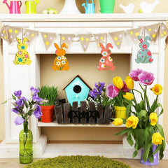 Decorative Easter mantel with bunting, birdhouse, and flowers.