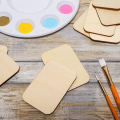 Beige cardboard shapes, paintbrushes, and a color palette on a wooden surface