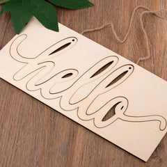 Wooden cutout letters spelling 'Hello' on a wooden surface with leaves and twine.