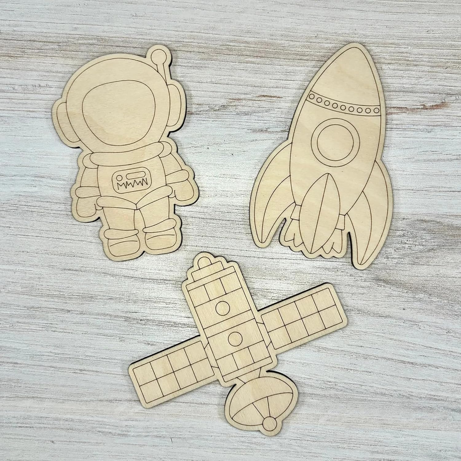 Wooden cutouts of an astronaut, rocket, and airplane on a wooden surface