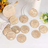Wooden milestone discs with engraved text on a white surface with flowers.