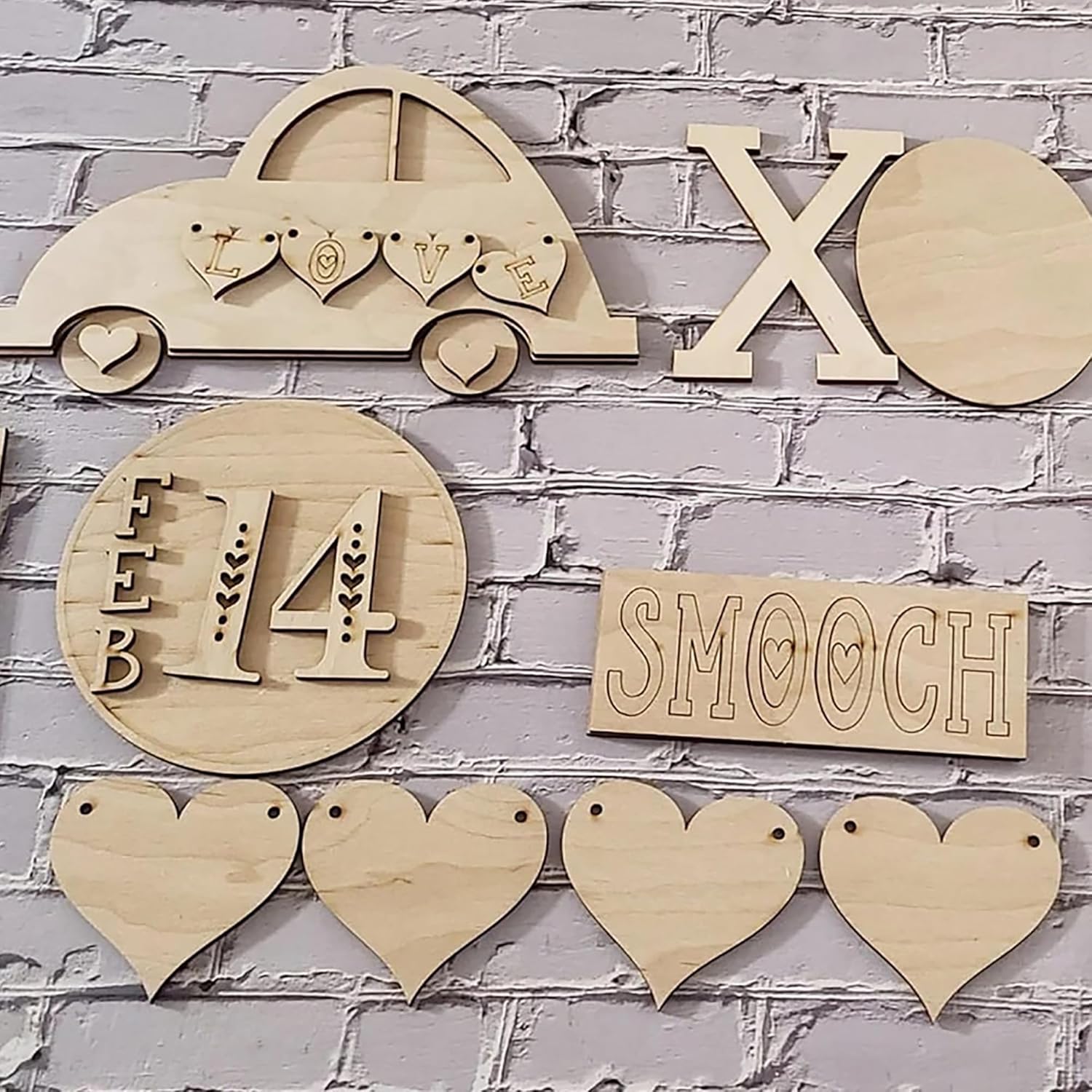 Wooden decorative items including hearts, 'LOVE', 'XO', 'FEB 14', and 'SMOOCH' on a brick wall background.