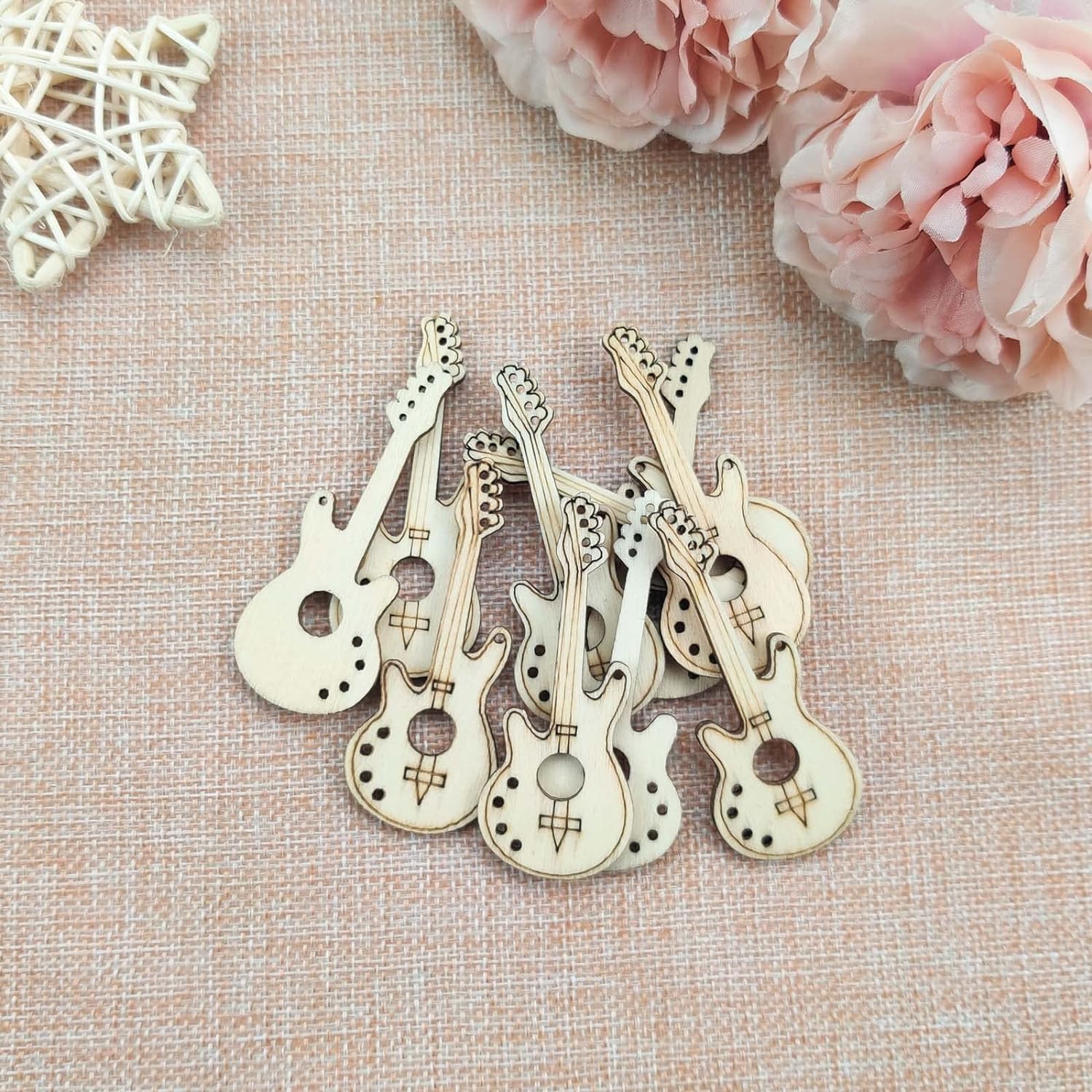 Wooden guitar-shaped bottle openers on a textured surface with pink flowers.