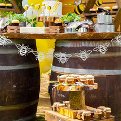Honey display with jars and a cake on a wooden table, decorated with bee-themed elements.
