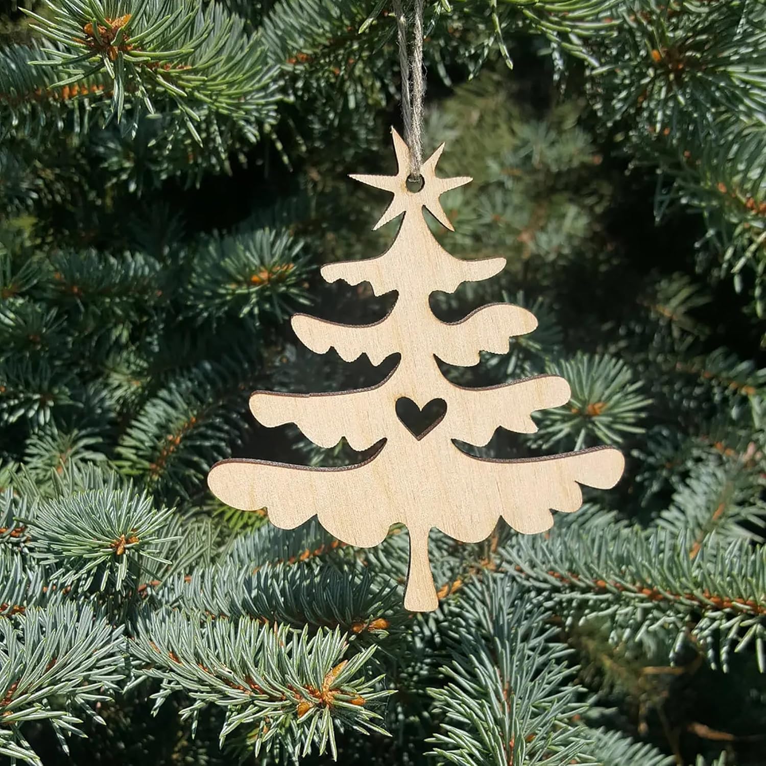 Wooden Christmas tree ornament hanging on a green pine branch
