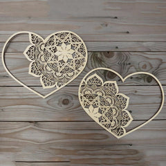 Two heart-shaped laser cut decorative pieces on a wooden surface
