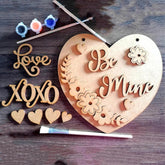 Wooden heart-shaped plaque with 'Be Mine' and other decorative elements on a wooden surface.