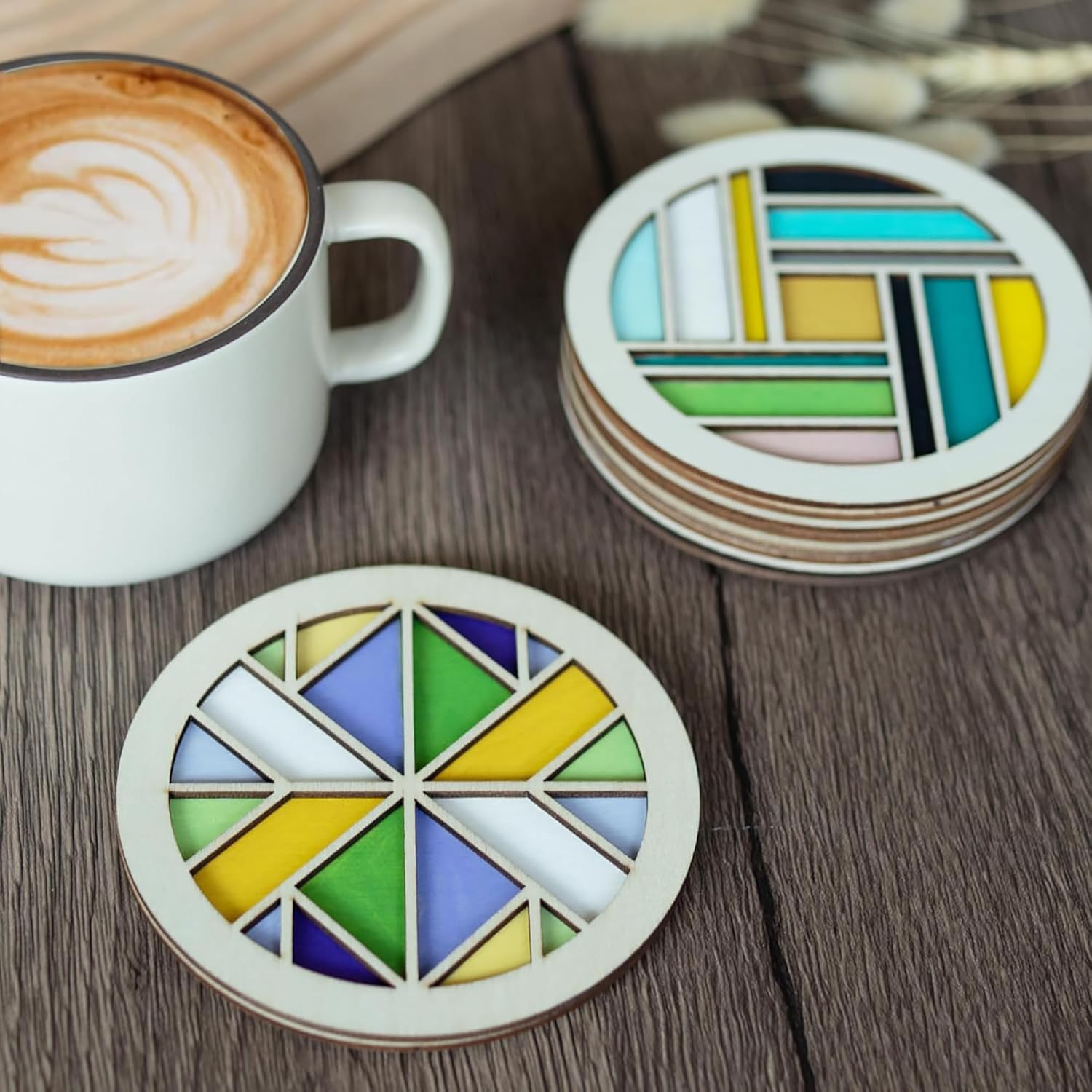 Colorful geometric coasters on a wooden surface with a cup of coffee.