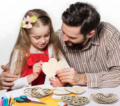Man and young girl crafting wooden heart shapes together on a table.