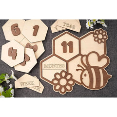 Wooden baby milestone cards with numbers and a bee design on a textured surface.