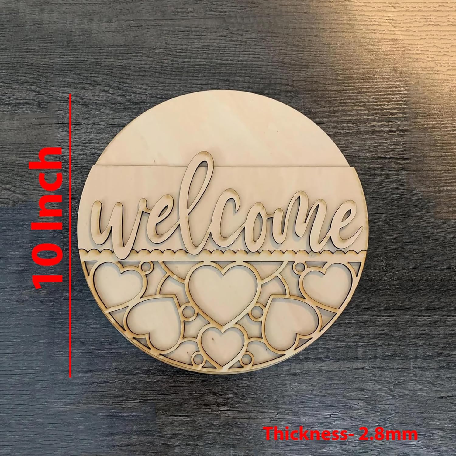 Wooden round decorative piece with 'welcome' text and heart designs, on a dark wooden surface.