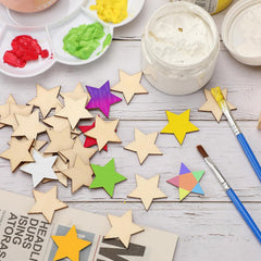 Colorful star-shaped craft materials on a table with paint and brushes.