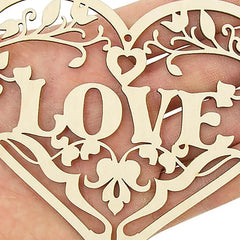 Decorative heart-shaped cutout with 'LOVE' text held between fingers
