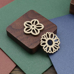 Gold floral earrings on a wooden stand with a colorful background