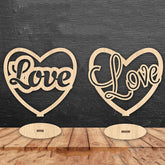 Two wooden heart-shaped signs with 'Love' engraved on them against a dark wooden background.