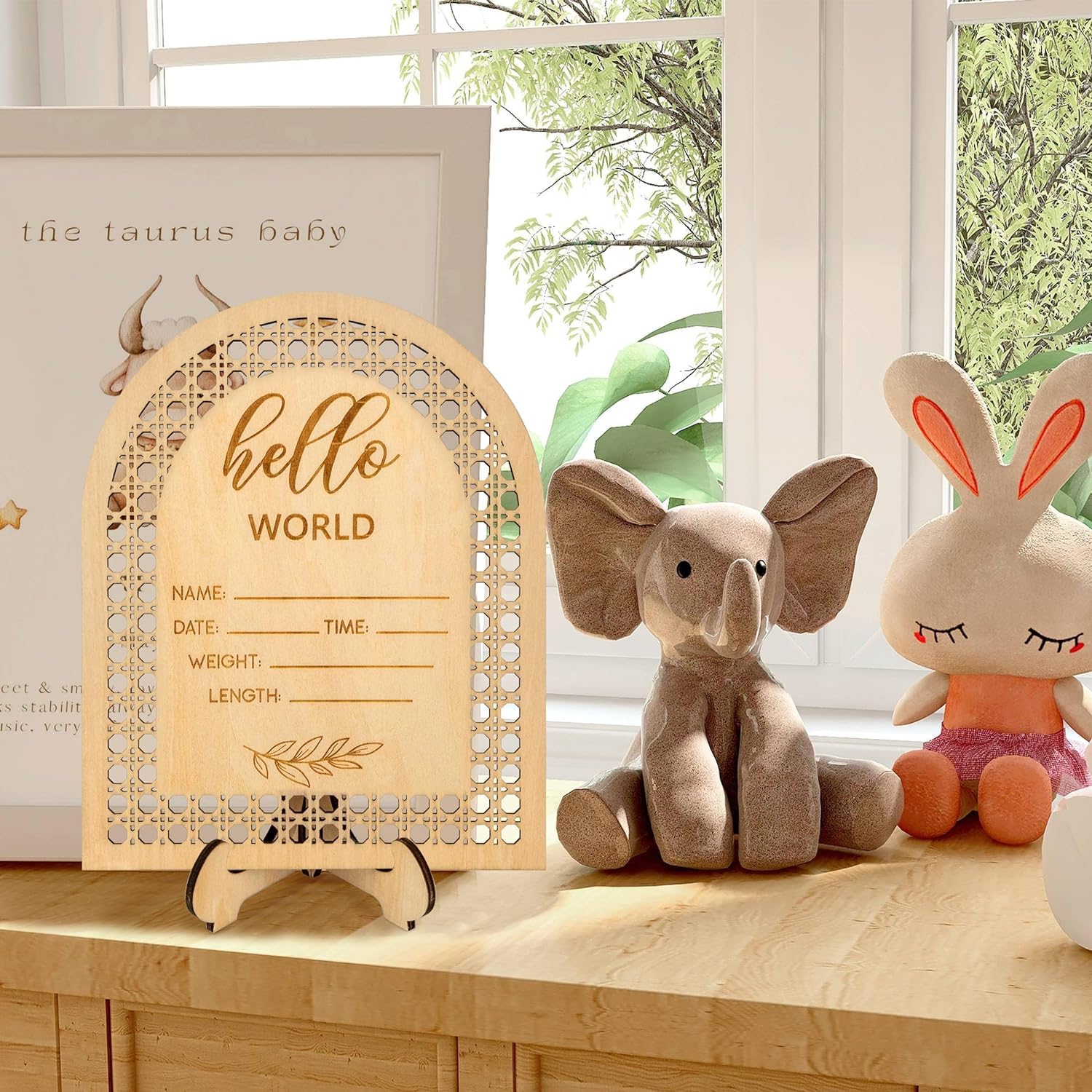 Wooden baby announcement sign with decorative elements on a table.