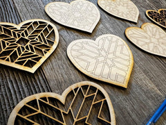 Heart-shaped wooden cutouts with geometric patterns on a wooden surface
