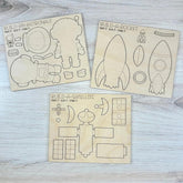 Three wooden templates for building an astronaut, rocket, and satellite on a light wooden surface.