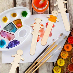 Wooden craft figures, paintbrushes, and paint palette on a wooden surface