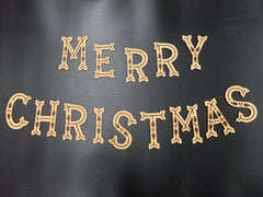 Wooden 'Merry Christmas' decoration on a black background