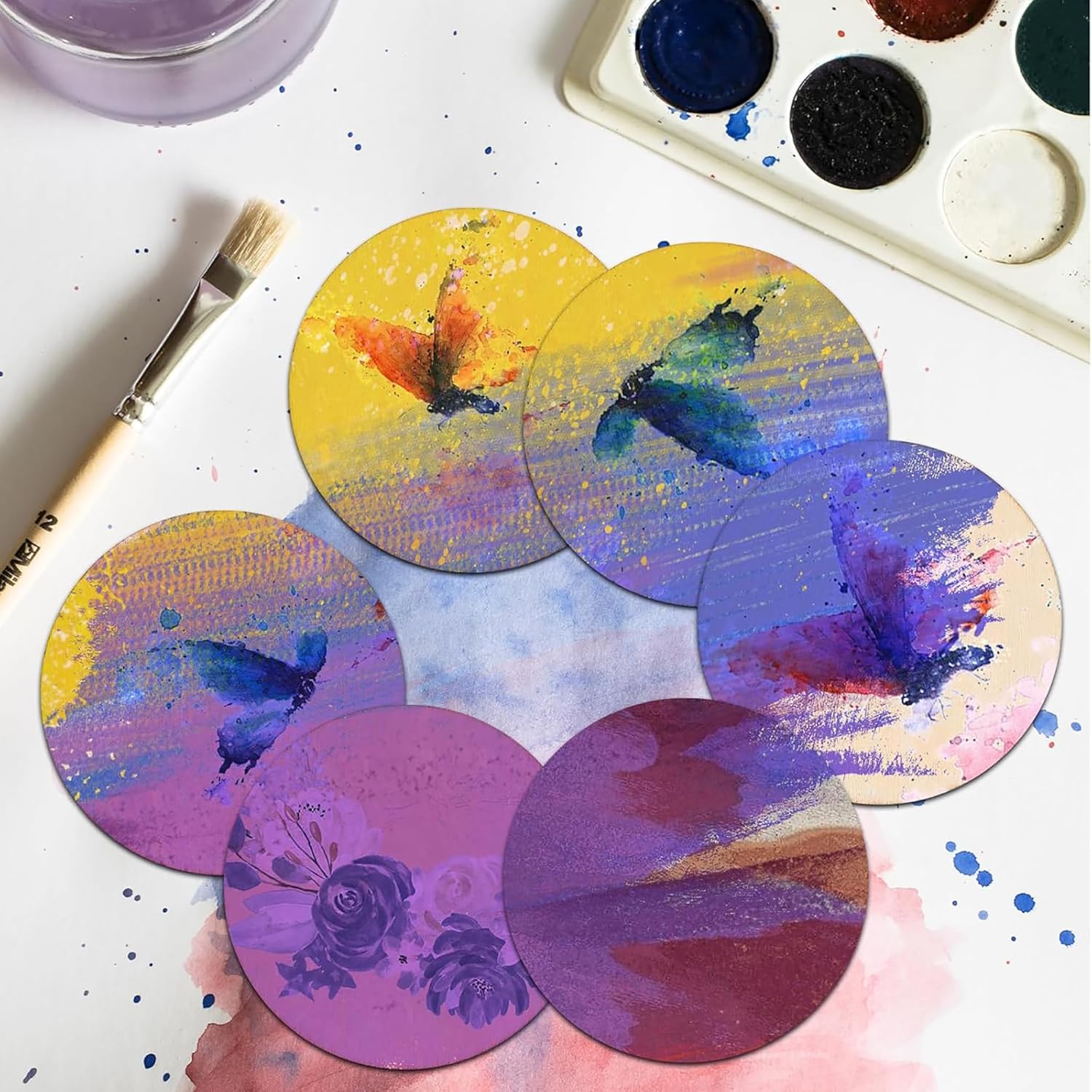 Colorful butterfly coasters on a white surface with paint supplies.