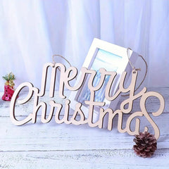 Wooden 'Merry Christmas' sign with a photo frame and pine cone on a light blue background