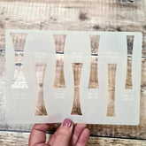 Transparent face mask with cut-out designs held by a hand on a wooden surface