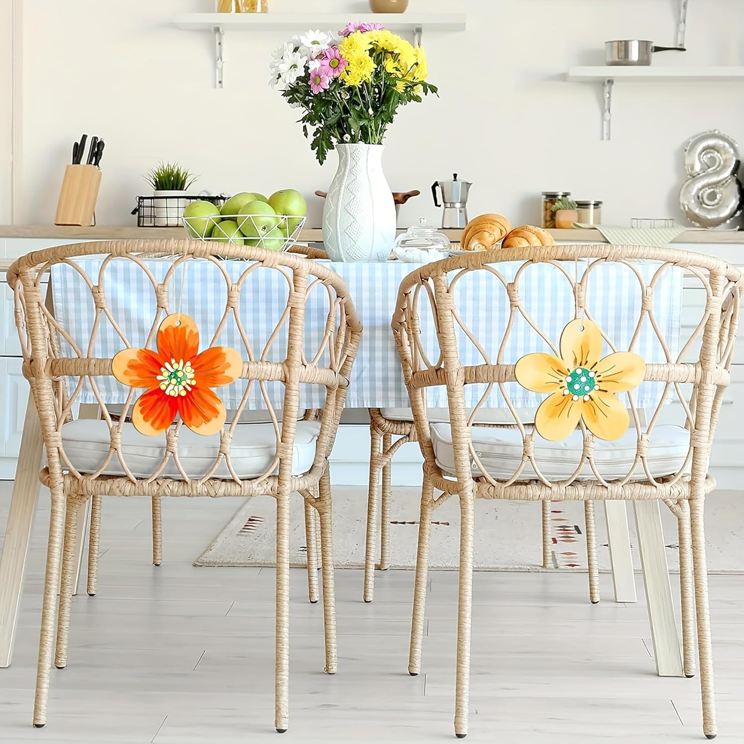 Dining area with wicker chairs featuring floral designs, a table with fruits, and a vase of flowers.