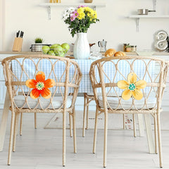 Dining area with wicker chairs featuring floral designs, a table with fruits, and a vase of flowers.