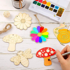 Colorful wooden ornaments being painted with a watercolor set on a wooden surface.