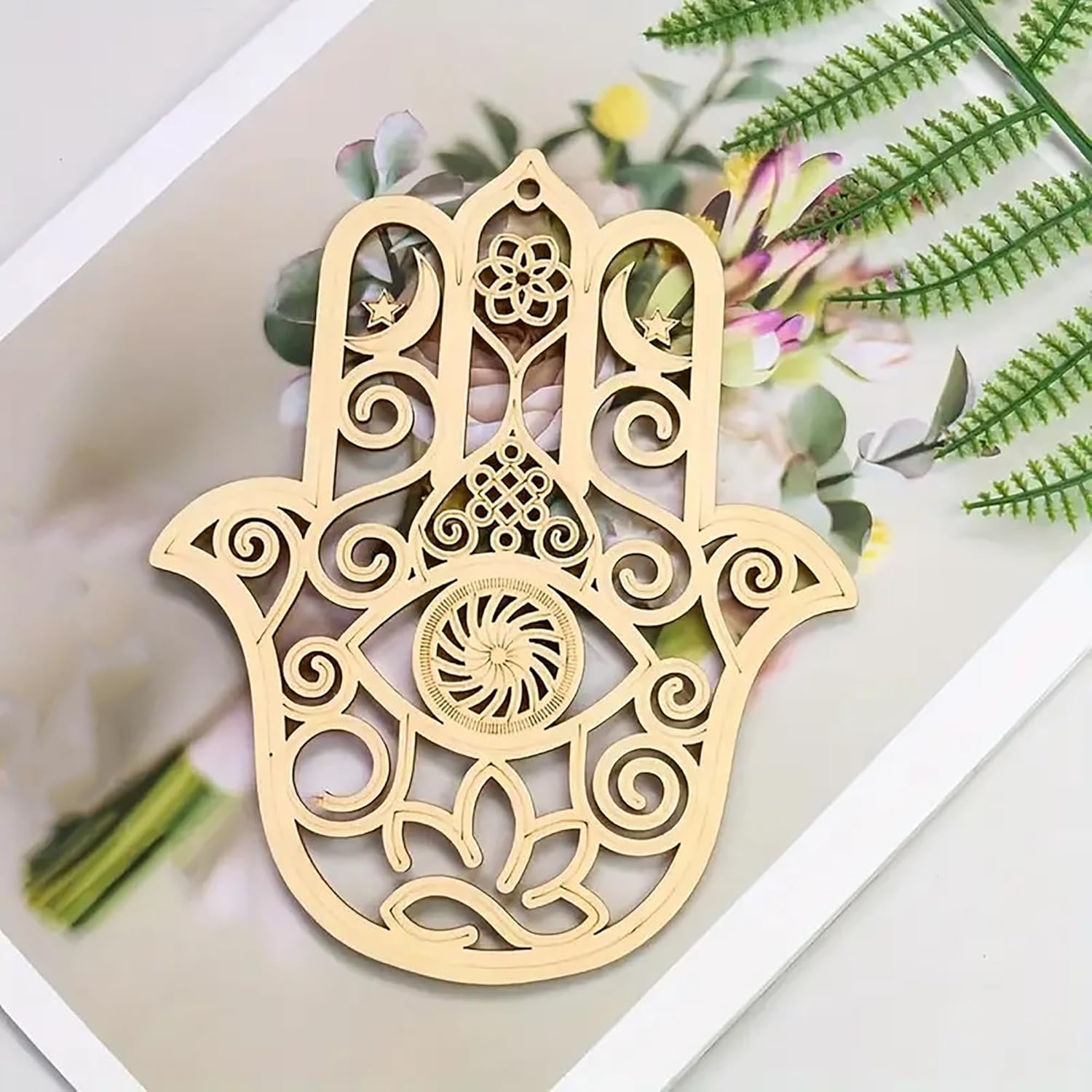Decorative gold Hamsa hand pendant on a floral background