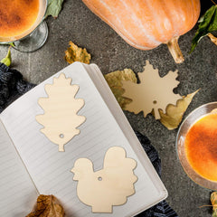 Wooden leaf and turkey cutouts on a notebook with pumpkins and drinks in the background