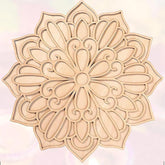 Decorative wooden mandala with intricate patterns on a light pink background