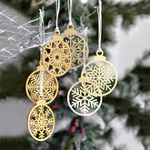 Gold snowflake Christmas ornaments hanging against a blurred Christmas tree background