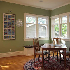 Dining room with wooden table and chairs, green walls, and large windows.