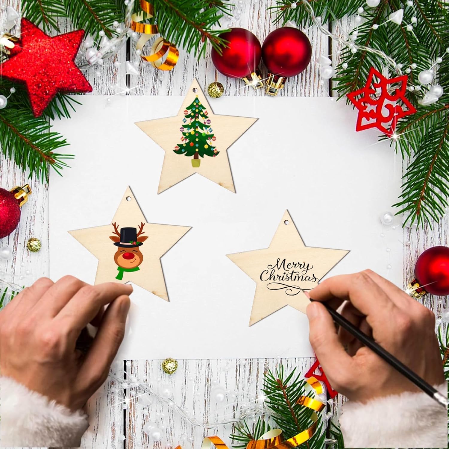 Person painting wooden star ornaments with Christmas decorations on a rustic wooden surface.