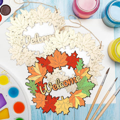 Wooden wreath with 'Welcome' text and colorful leaves on a table with art supplies.