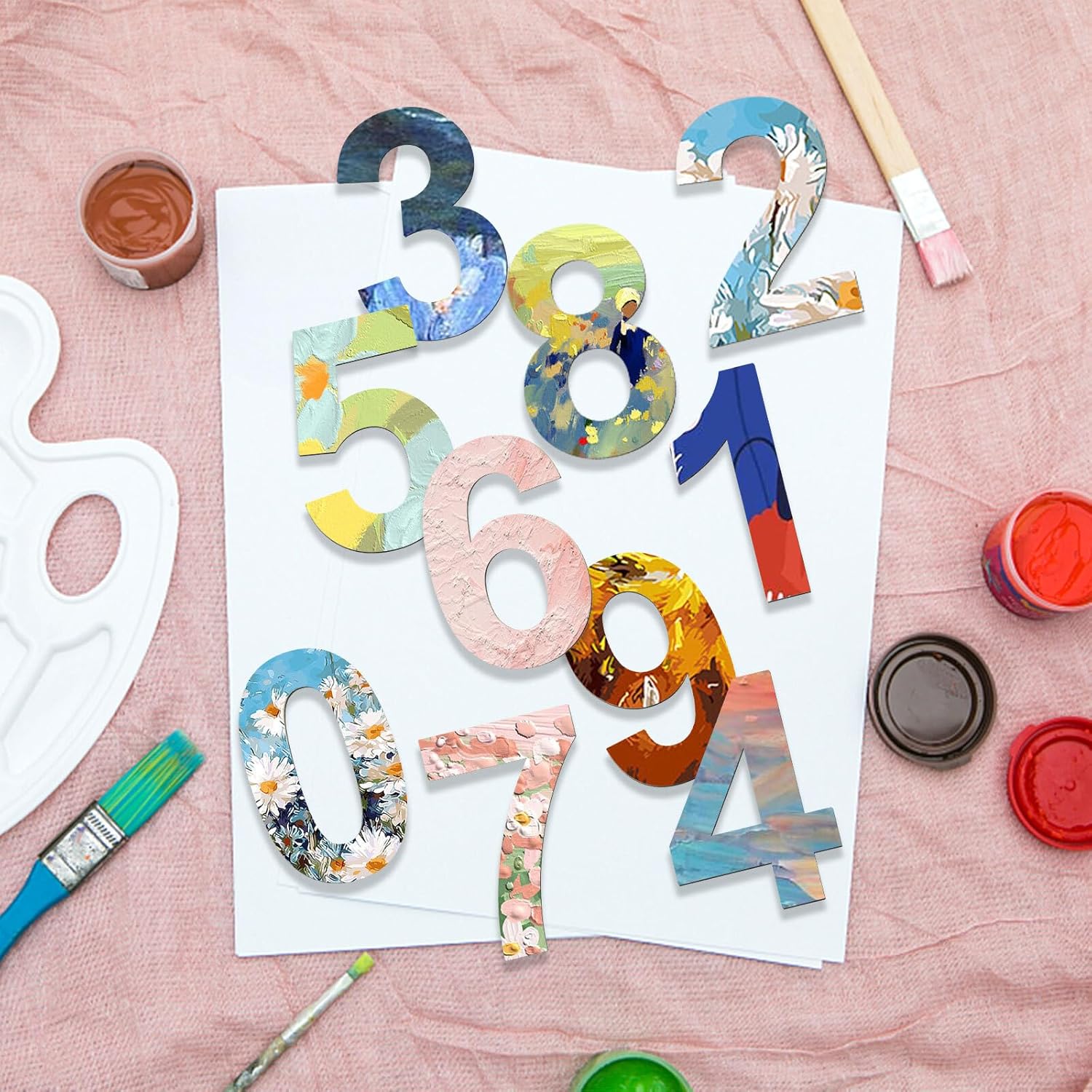 Colorful numbers on a piece of paper with painting supplies on a pink surface