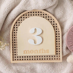 Baby milestone board with '3 months' on a soft fabric background