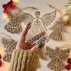 Decorative angel ornaments with a hand holding one, surrounded by more angel ornaments and Christmas decorations.