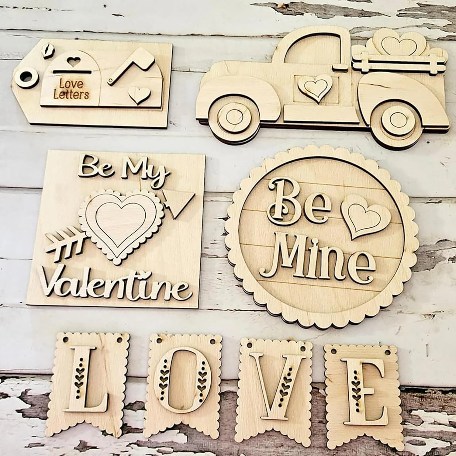 Wooden decorative items with 'Be My Valentine', 'Be Mine', and 'LOVE' text on a rustic wooden background.