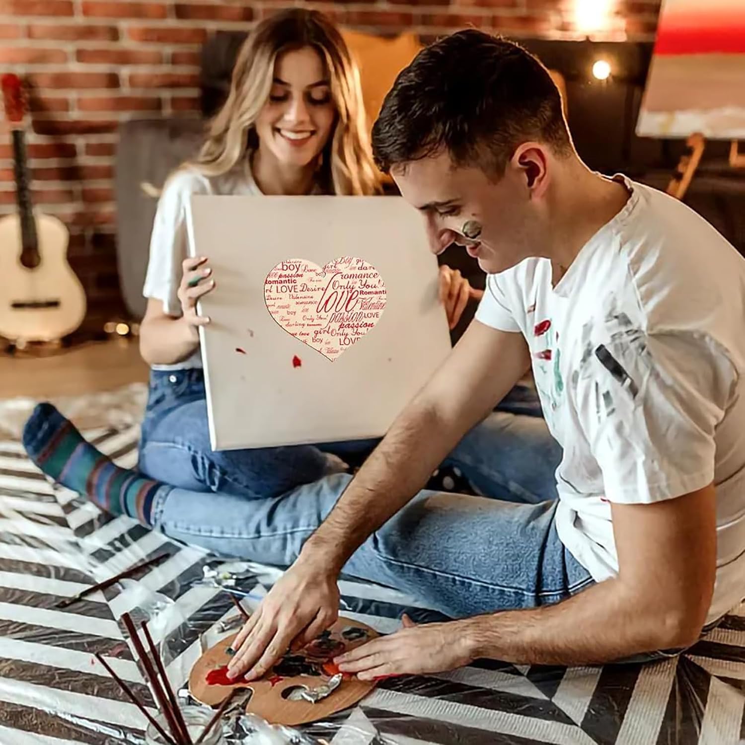Man and woman sitting on a bed, looking at a laptop together.