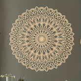 Decorative wall mandala on a plain wall with a plant in the corner.