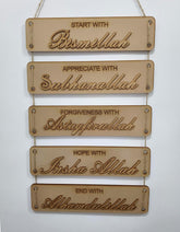 Wooden wall hanging with engraved phrases on a white background