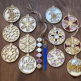 Decorative wooden ornaments with snowflake designs and paint supplies on a wooden surface