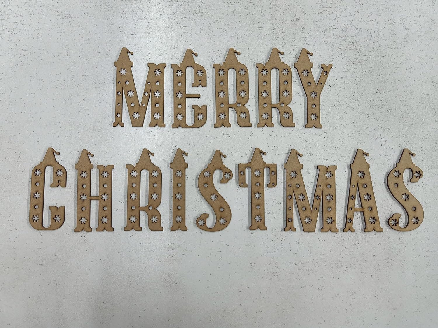 Decorative wooden cutout letters spelling 'Merry Christmas' on a textured surface.