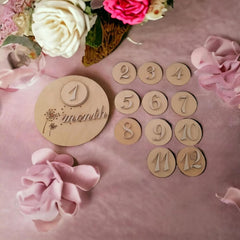 Wooden milestone cards with numbers on a pink background with flowers