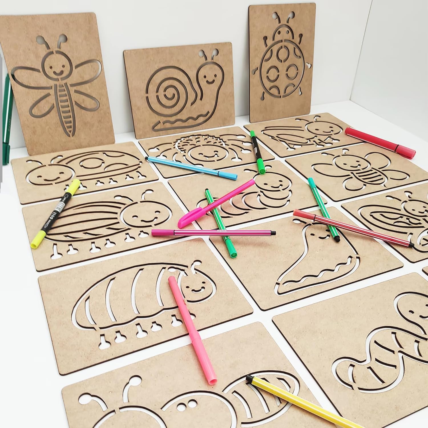 Set of cardboard stencils with animal designs and markers on a white background